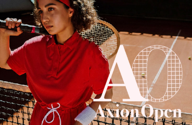Donna vestita di rosso, pronta a colpire la pallina con la racchetta, davanti a una rete e logo del torneo Avion Open.
