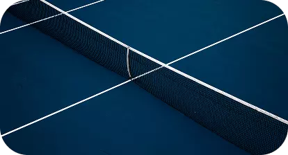 Campo da tennis con linee bianche che definiscono il campo e la pallina vicino al guantone della rete.