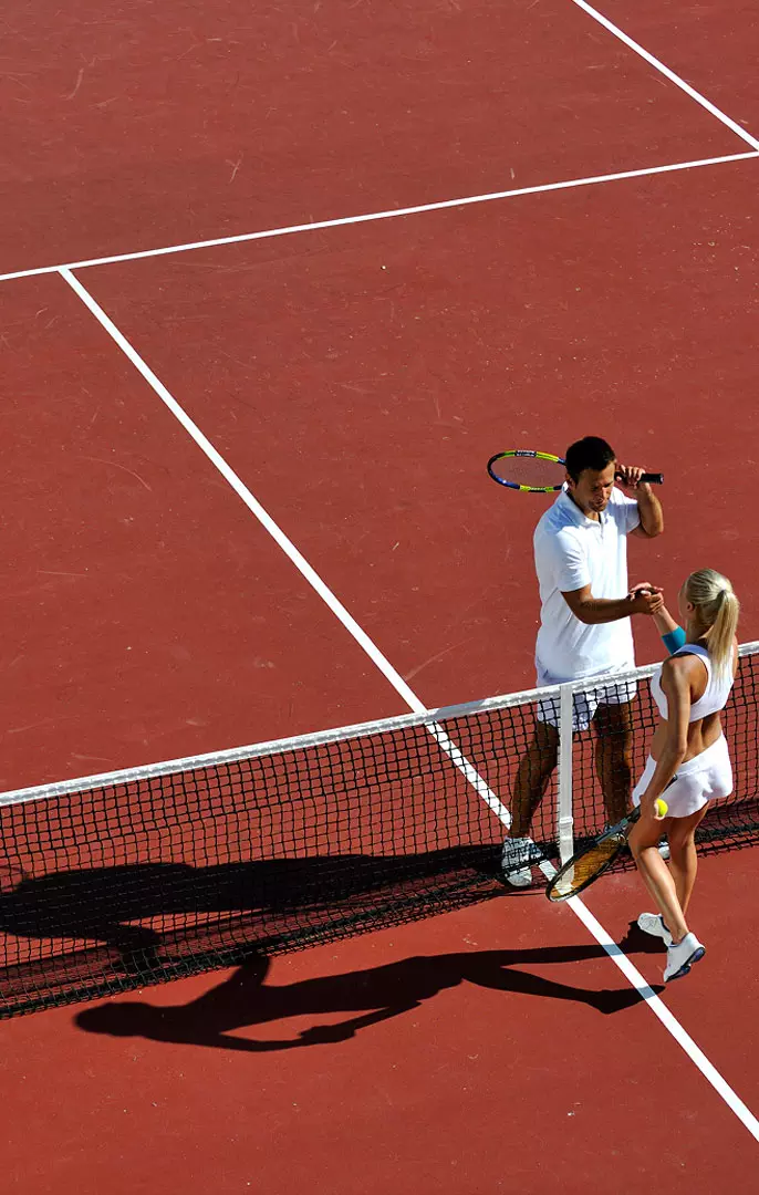 Due tennisti su un campo da tennis, dialogano vicino alla rete