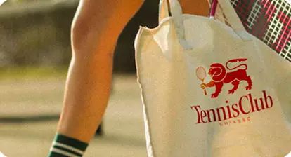 Persona con borsa da tennis con logo Tennis Club Chiasso, sfondo sportivo all’aperto, colori vividi e dettaglio visibile della tracolla.